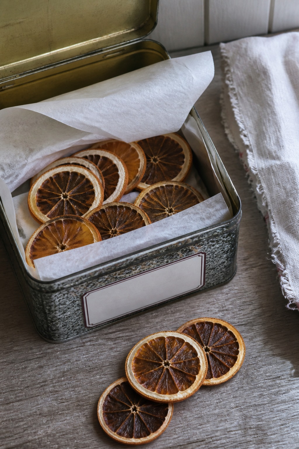 Dried citrus slices stored in a tin between tissue
