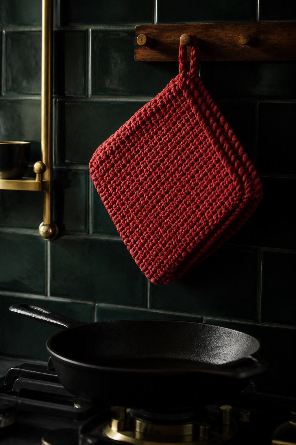 Double-thick knit potholder with a short hanging loop beside a pan
