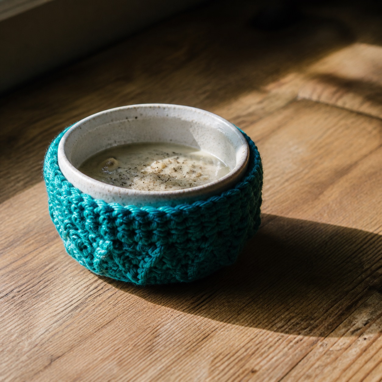 Knit bowl cozy holding a ceramic soup bowl