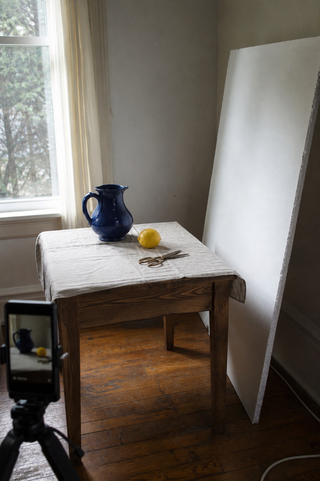 Still-life setup: table beside a window, bounce board, three objects
