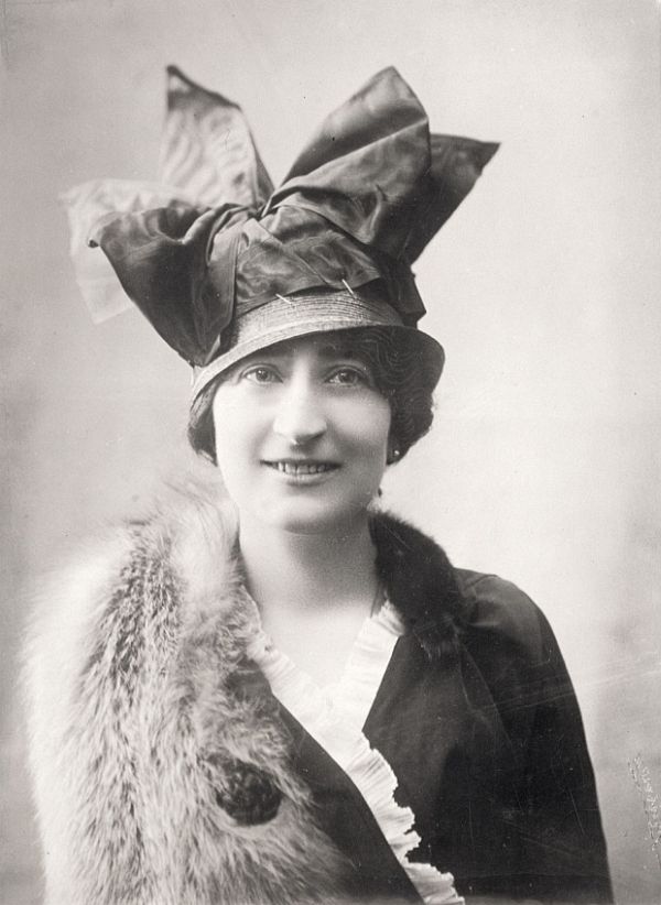 Portrait showing a structured early-1910s hat with upright trim