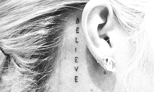 BELIEVE lettering tattoo behind the ear