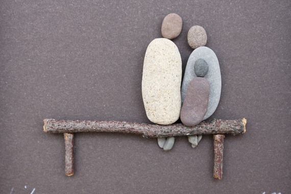Family of three pebble figures on a twig bench