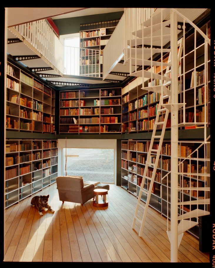 Two-story home library with spiral stair and reading chair