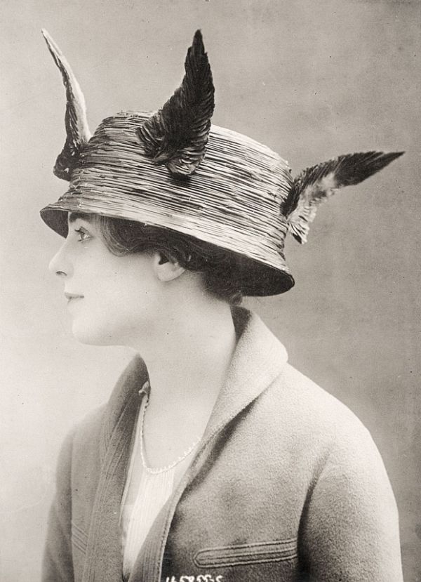 Woman in period dress with a sculptural hat silhouette