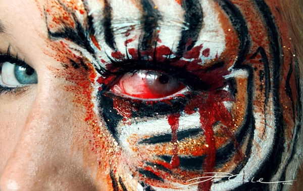 Tiger-stripe eye makeup with red contact effect and painted drips