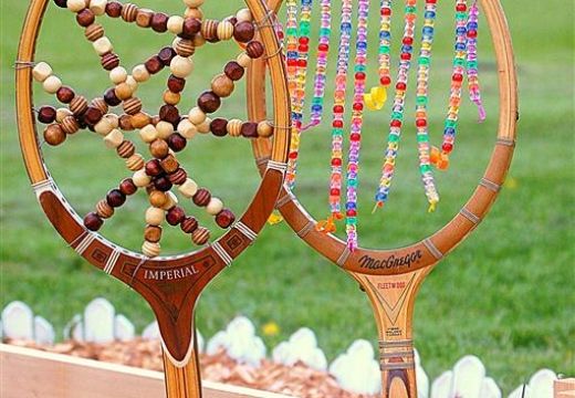 Beaded vintage tennis rackets in a garden bed