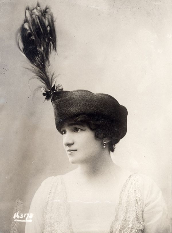 Edwardian-era woman with an elevated hat and soft studio lighting