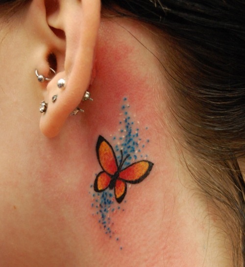orange butterfly tattoo with blue dots behind ear