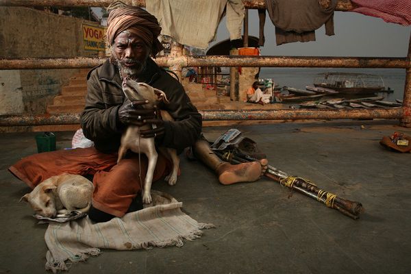 Man with turban holding a dog near crutches and a prosthetic leg