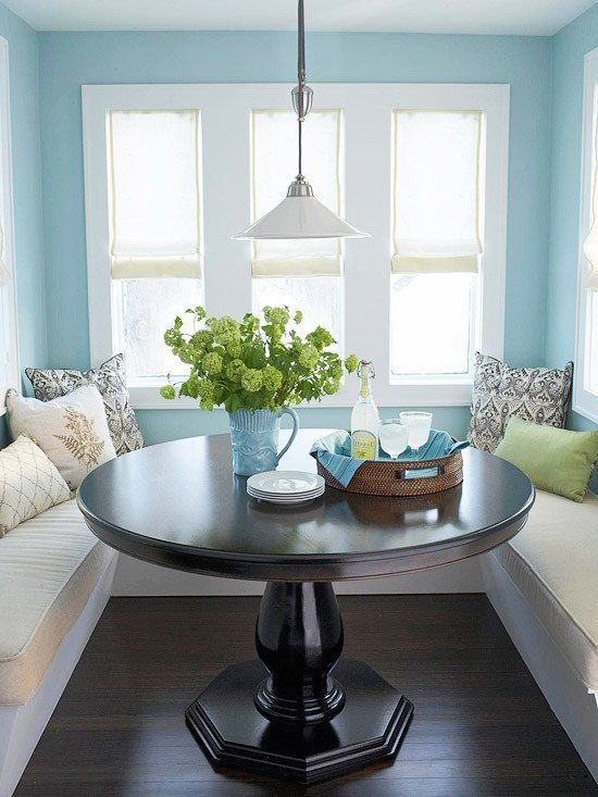 Sky blue U-shaped banquette with dark wood pedestal table
