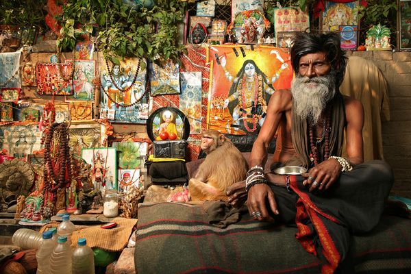 Holy man with a monkey before deity posters
