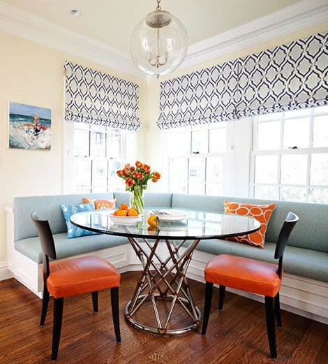 Aqua banquette orange chairs and geometric Roman shades