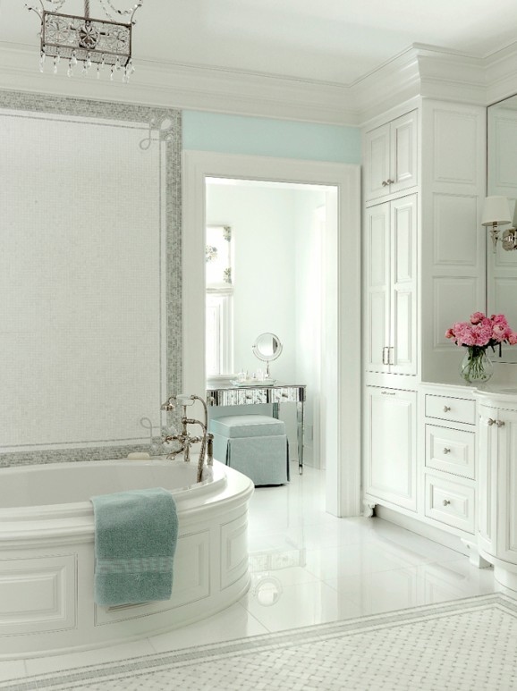 Bright master bathroom with soaking tub, white cabinetry, and crystal chandelier