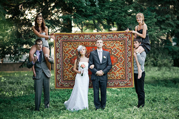 Couple posing while friends hold up a large rug as a backdrop