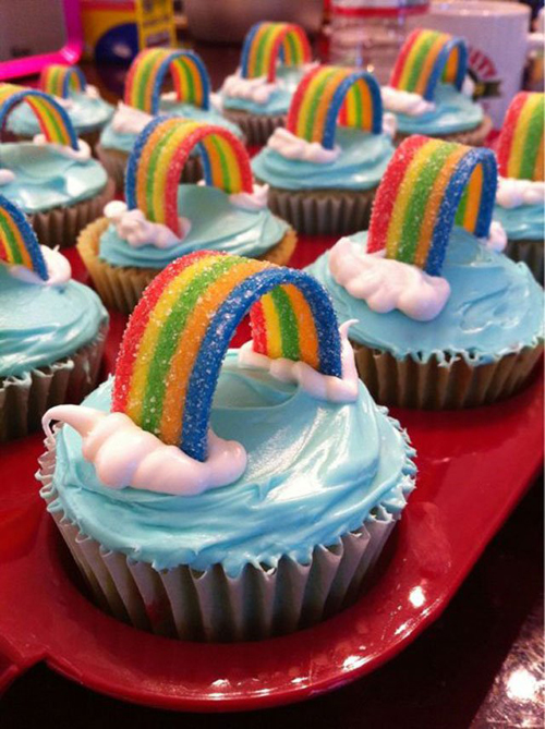 Rainbow cupcakes with sour candy belts and frosting clouds
