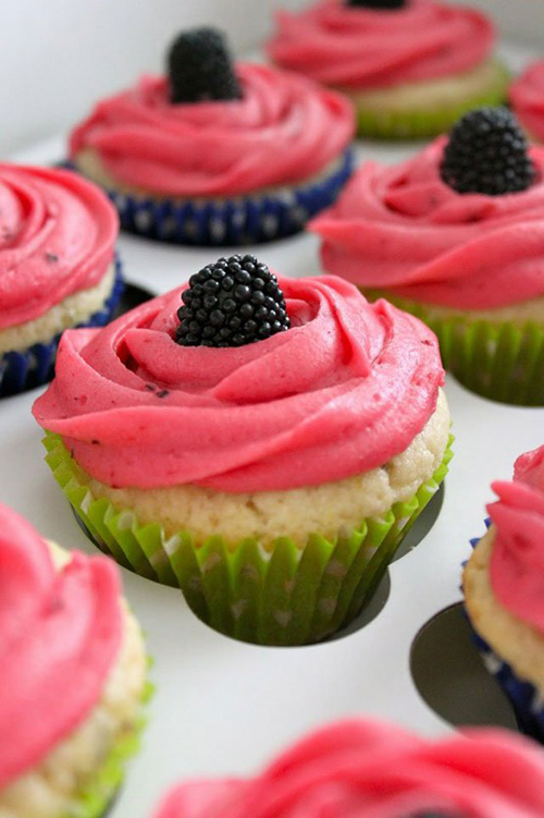 Pink frosted cupcakes topped with fresh blackberries