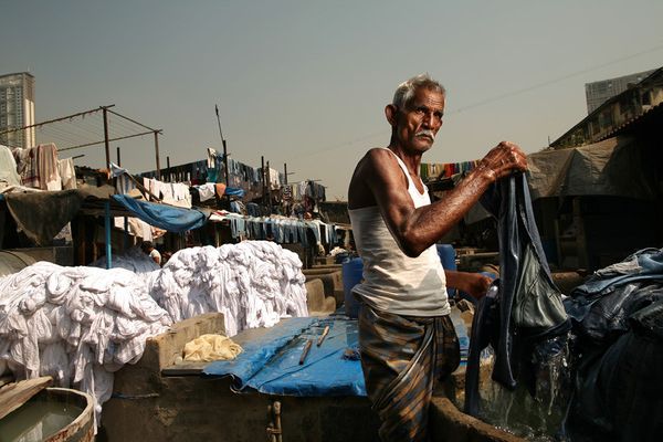 Washerman lifting wet cloth at an outdoor laundry