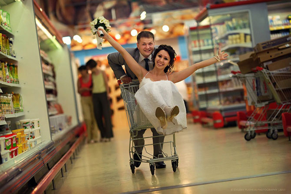 Bride in a shopping cart pushed by the groom in a supermarket aisle