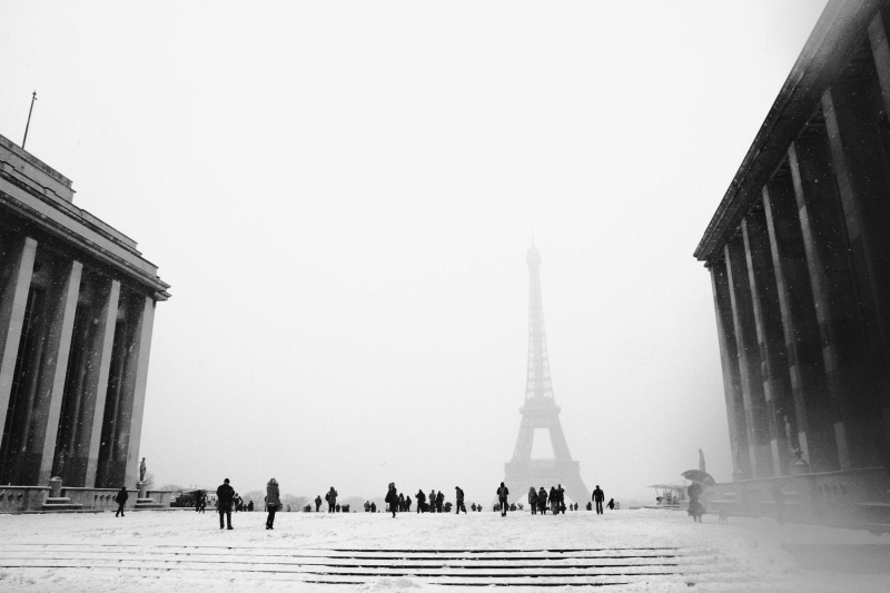 Black-and-white snowy Trocadéro view toward a fogged Eiffel Tower