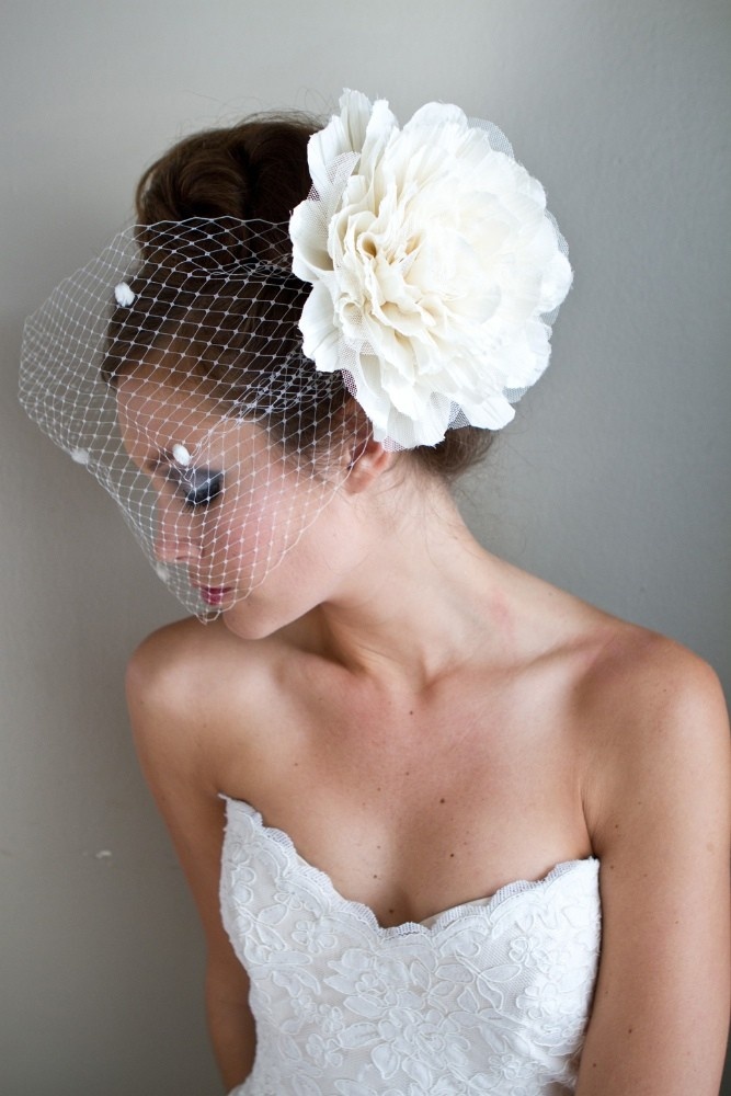 Asymmetrical birdcage veil pinned to one side of the hair
