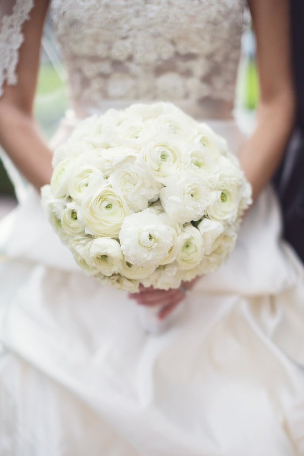 white ranunculus bridal bouquet held against lace gown
