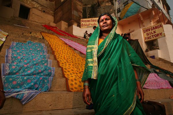 Woman in green sari on steps with textiles drying