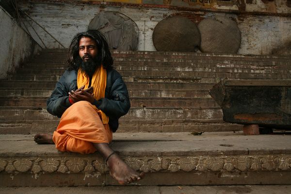 Ascetic in orange cloth and quilted jacket on stone steps