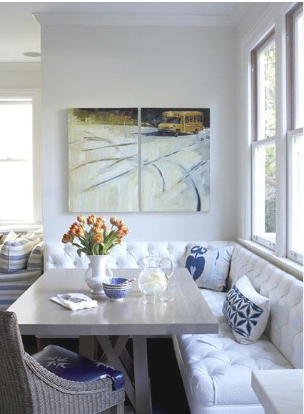 White tufted banquette with trestle table and diptych art