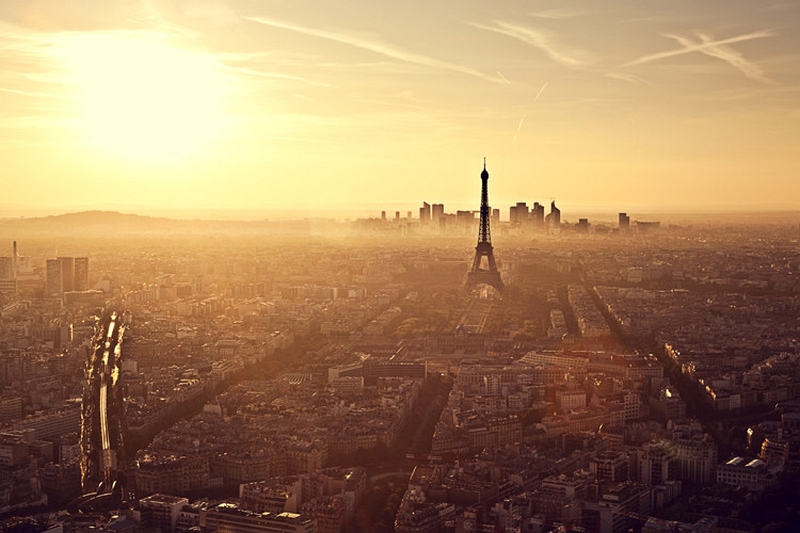 Hazy golden-hour Paris skyline with the Eiffel Tower and lens flare